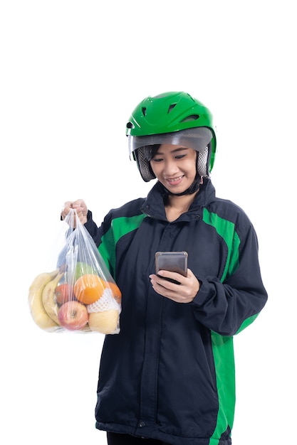 Mensageira de uber entrega feminina usando capacete traz mantimentos em um saco plástico isolado sobre fundo branco
