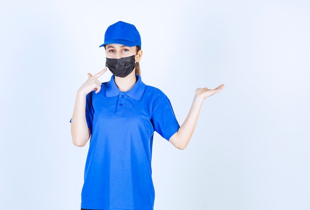 Mensageira feminina com máscara e uniforme azul e mostrando algo no lado direito