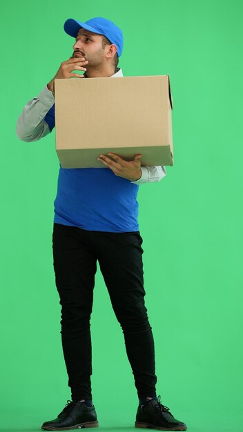 mensageiro masculino de comprimento completo segurando uma caixa em um fundo verde