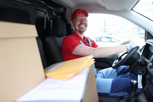 Mensageiro sorridente sentado no carro como motorista