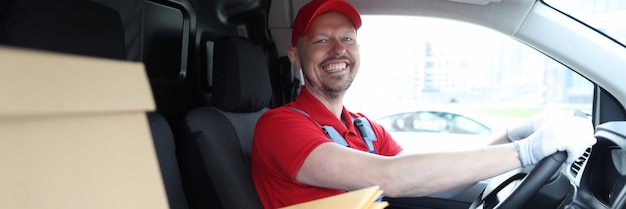 Mensageiro sorridente sentado no carro como motorista