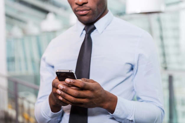 Mensagem de digitação do empresário. Imagem recortada de jovem africano de camisa e gravata