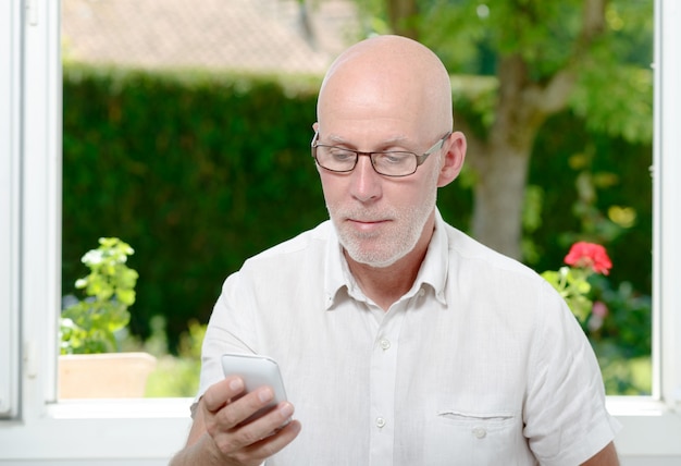 Mensagem de leitura do homem sênior no smartphone