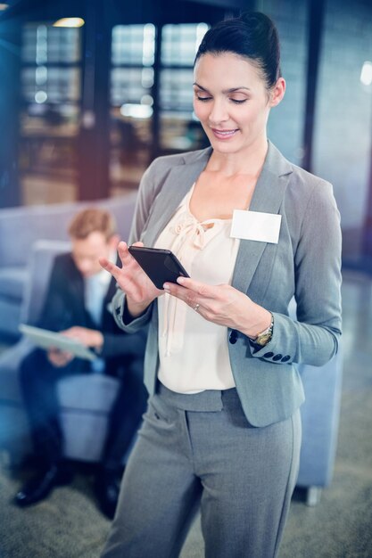 Mensagem de texto da mulher de negócios no telefone celular no escritório