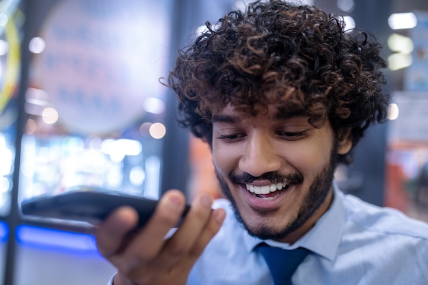 Mensagem de voz. Jovem empresário de cabelos cacheados gravando uma mensagem de voz