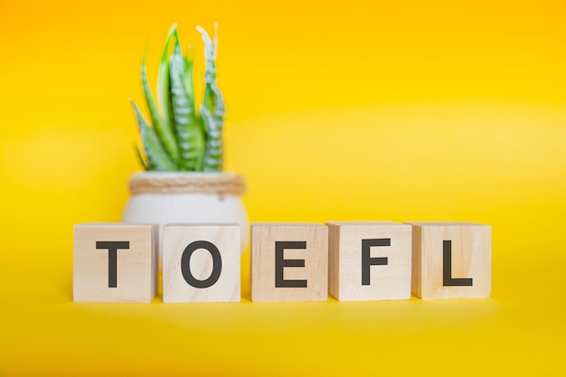 Mensagem TOEFL feita com blocos de madeira, fundo amarelo