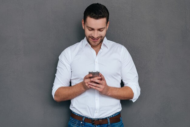 Mensagens de texto de negócios. Jovem bonito falando no telefone inteligente