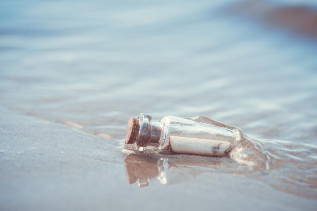 Mensaje en la botella arrastrada desde el mar contra la puesta de sol