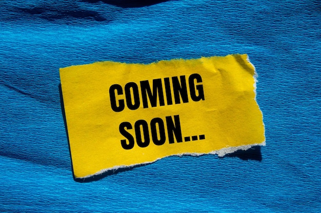 Mensaje de pronto venido escrito en un pedazo de papel amarillo rasgado con fondo azul Símbolo conceptual de pronto venida Copiar espacio