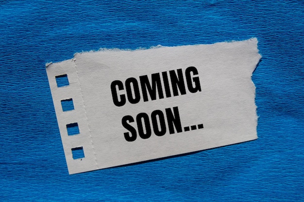Mensaje que viene pronto escrito en un pedazo de papel rasgado con fondo azul Símbolo conceptual que viene pronto Copiar espacio