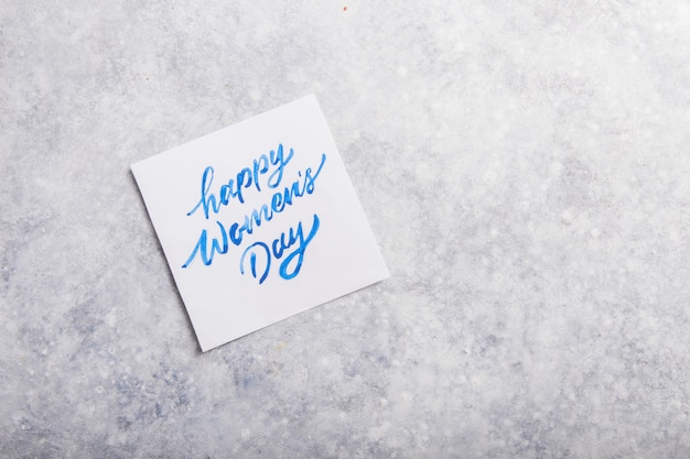 Foto mensaje de tarjeta con feliz día de la mujer en mesa gris