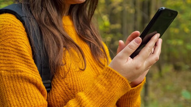 Mensaje de tipos de joven turista en el teléfono móvil en el bosque