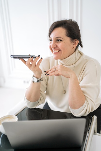Un mensaje de voz graba un texto que una mujer alegre usa un teléfono y una computadora portátil que un trabajador independiente trabaja en casa