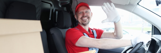 Mensajero conductor masculino en la cabina del coche agitando su mano en señal de saludo