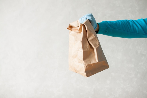 Mensajero de entrega de alimentos sostiene una gran bolsa de papel en sus manos
