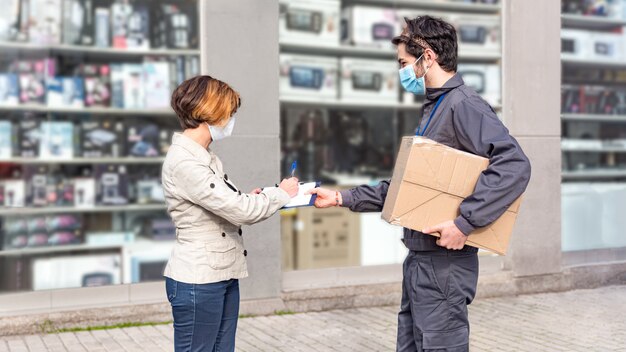 El mensajero entrega la caja a la mujer. La mujer firma el paquete.