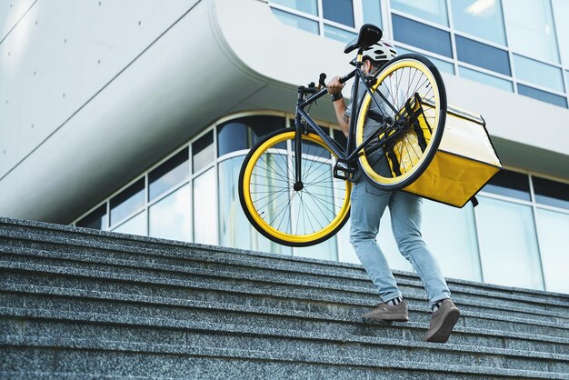 Mensajero de entrega urgente con bolsa aislada que lleva bicicleta