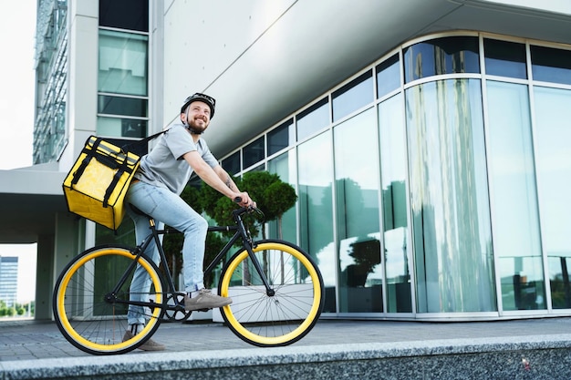 Mensajero de entrega urgente de pie en bicicleta con bolsa aislada