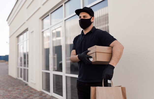Mensajero con máscara protectora y guantes médicos entrega comida para llevar
