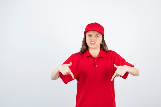 mensajero mujer joven en uniforme rojo apuntando.