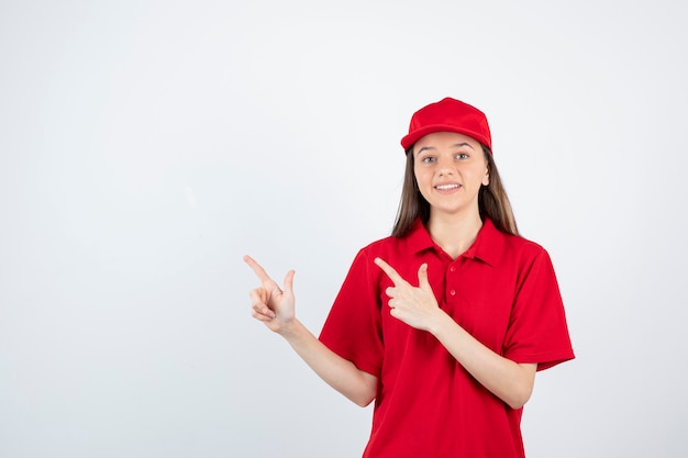 mensajero mujer joven en uniforme rojo apuntando.