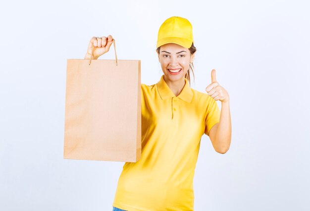 Mensajero mujer sosteniendo una bolsa de cartón y mostrando signo de disfrute.