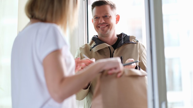 El mensajero sonriente entrega el paquete a la mujer