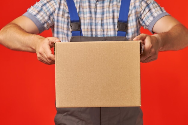 Foto el mensajero con traje de trabajo trajo una caja de cartón.