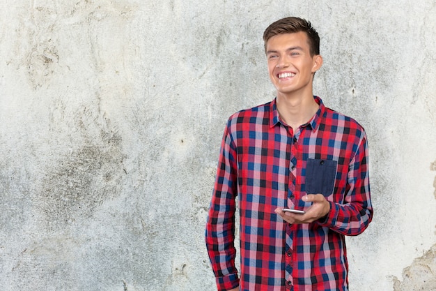 Foto mensajes de texto de hombre casual joven en su teléfono inteligente