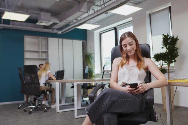 Mensajes de texto de joven empresaria en su teléfono inteligente