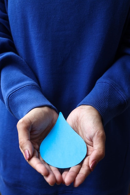 mensch, der blauen pullover trägt, der papierwassertropfen hält. Weltwassertag, rettet das Wasser.