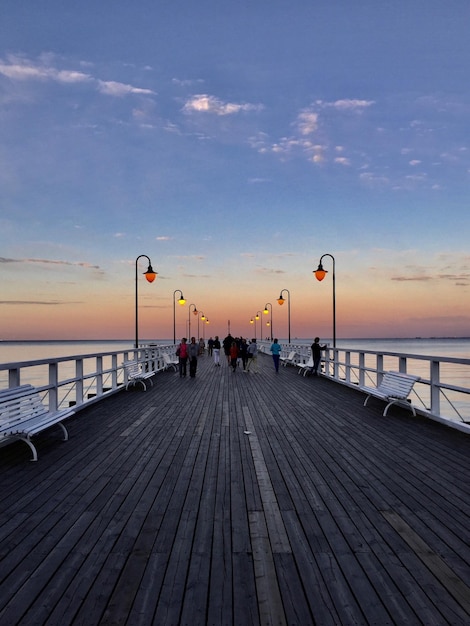 Menschen am Pier auf dem Meer gegen den Himmel bei Sonnenuntergang