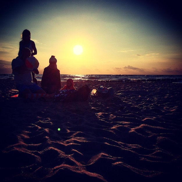 Foto menschen am strand bei sonnenuntergang