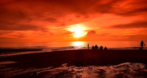 Foto menschen am strand gegen einen orangefarbenen himmel beim sonnenuntergang