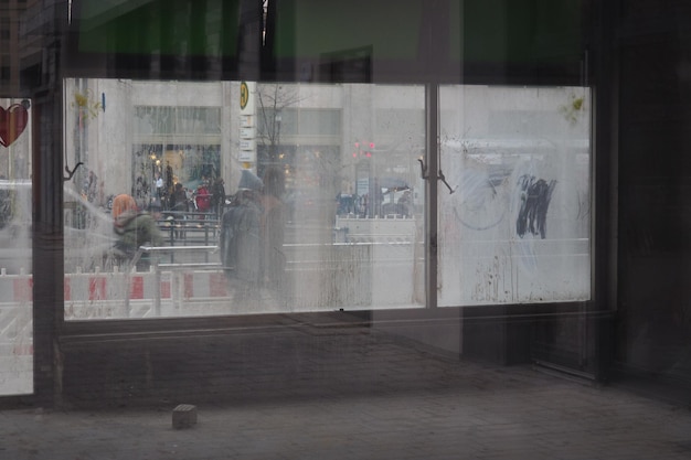 Menschen auf der Straße aus einem schmutzigen Glasfenster eines verlassenen Gebäudes