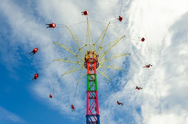 Menschen auf einem Karussell in großer Höhe gegen den Himmel.