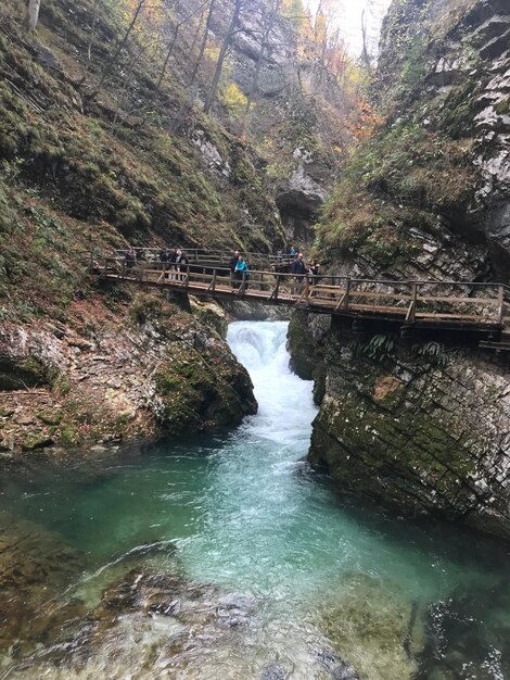 Foto menschen auf einer fußgängerbrücke über einen wasserfall inmitten von felsformationen im wald