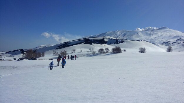 Foto menschen auf schneebedeckten bergen vor blauem himmel