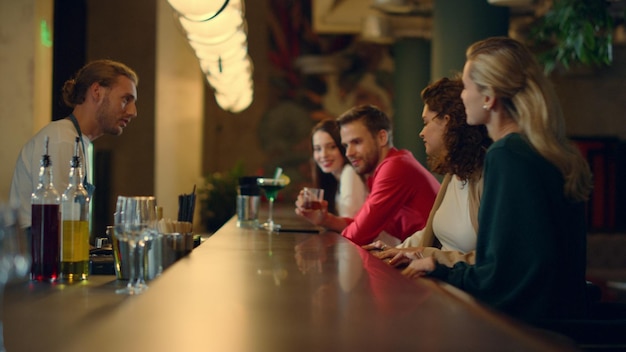 Menschen begrüßen sich in der Bar. Kollegen bestellen nach der Arbeit Cocktails