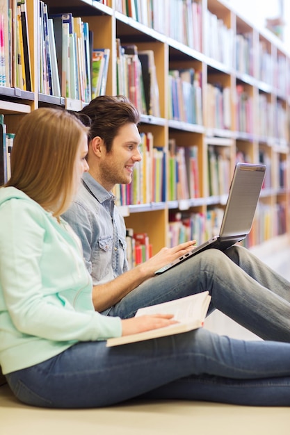 menschen, bildung, technologie und schulkonzept - glückliche schüler mit laptop-netzwerk in der bibliothek