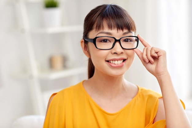 menschen, bildung, vision und porträtkonzept - glückliche asiatische junge frau oder jugendliche studentin mit brille zu hause