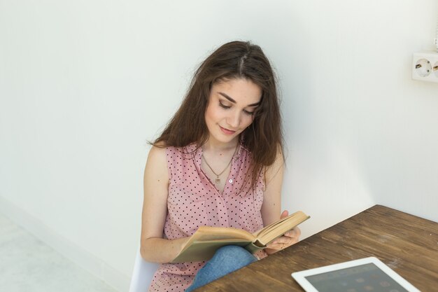 Menschen, Bücher und Bildungskonzept - Porträt der glücklichen Studentin, die mit einem Buch sitzt