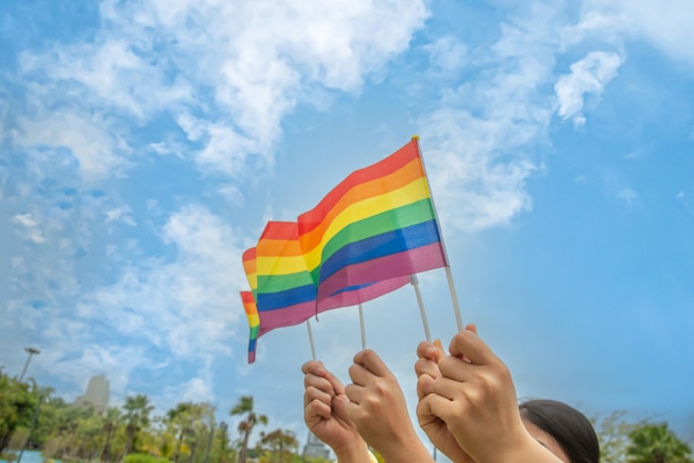 Menschen der Vielfalt hissen gemeinsam bunte LGBTQ-Regenbogenfahnen, ein Symbol für die LGBT-Gemeinschaft