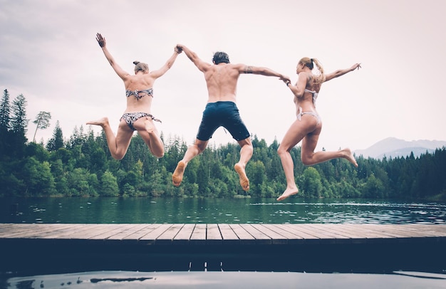 Menschen, die am See gegen den Himmel springen