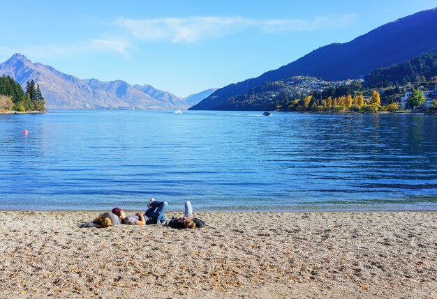 Menschen, die am Strand des Lake Wakatipu am sonnigen Tag, Queenstown, Südinsel von Neuseeland entspannen