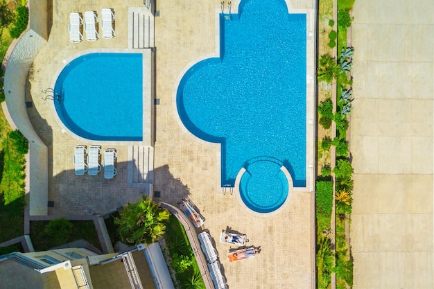 Menschen, die auf den Sonnenliegen in der Nähe des Pools liegen, Blick von oben