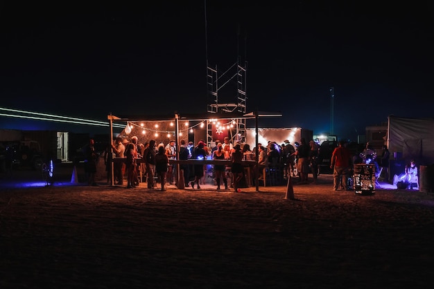 Menschen, die bei einem Festival in der Wüste dem Sonnenuntergang entgegengehen