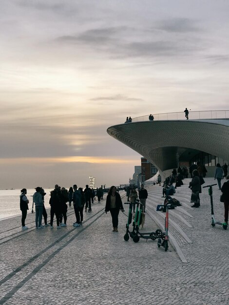 Menschen, die bei Sonnenuntergang am Meer vor dem Himmel spazieren gehen