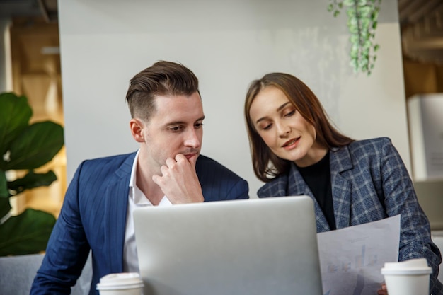 Menschen, die bei Startups arbeiten Zwei lächelnde Geschäftsleute und Brainstorming bei der Verwendung von laptopxA