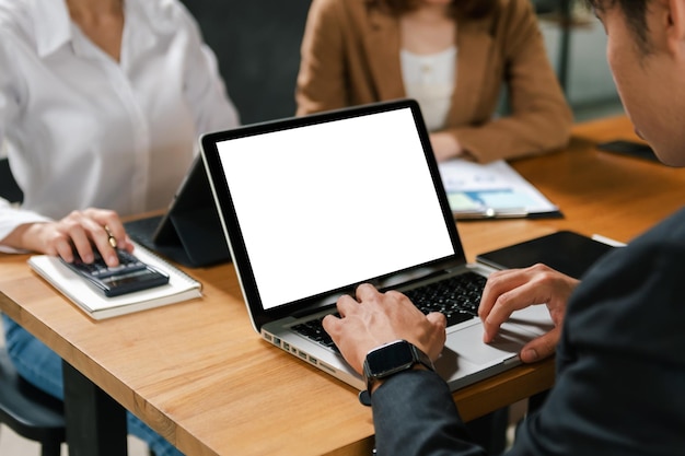 Menschen, die einen Mockup-Laptop auf einem Holztisch zusammen auf einem Schreibtisch mit Tablet verwenden und betrachten